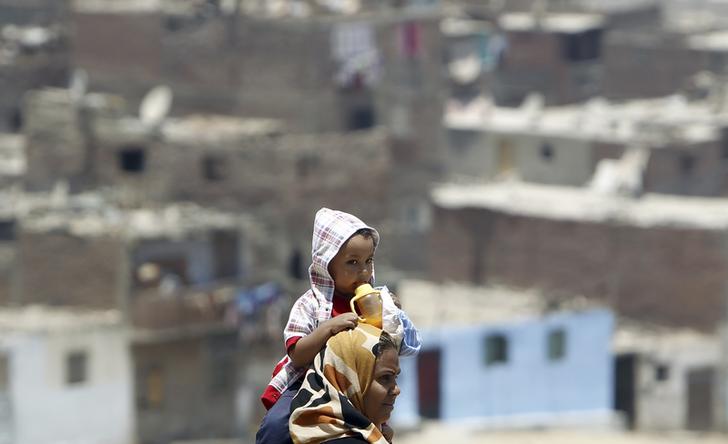 An Egyptian woman carries her child on her shoulders at Manshiyet Nasser shanty town in eastern Cairo