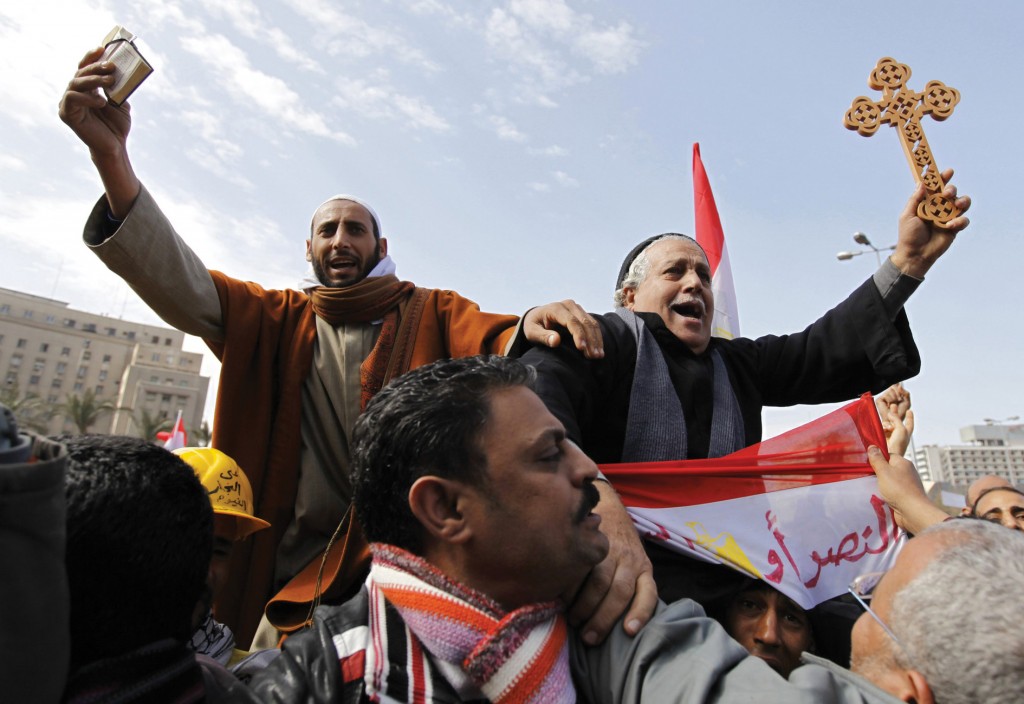 A Muslim holding the Koran (top L) and a Coptic Christian holding a cross in Cairo's Tahrir Square during the period of interfaith unity on February 6, 2011. Credit: Dylan Martinez