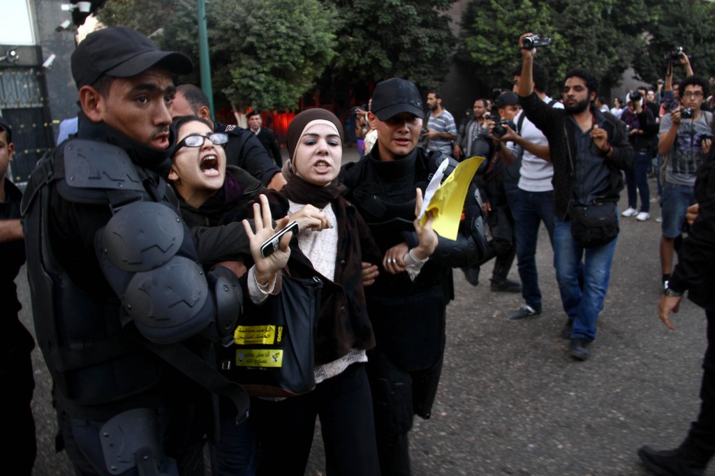 Activist Mona Seif detained by police officers during a protest in November 2013