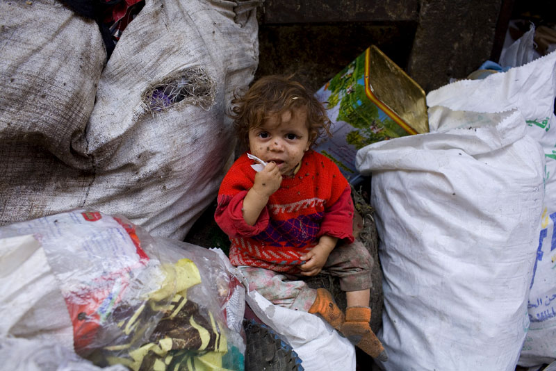 A young child sits in a pile of trash on the streets of Moqqatam, a suburb of Cairo which is home to a people known as the Zabaleen, which means, plainly enough, “the garbage collectors”. They are said to be the world’s greatest recyclers yet the Zabaleen also live in extreme urban squalor. Credit: Peter Dench