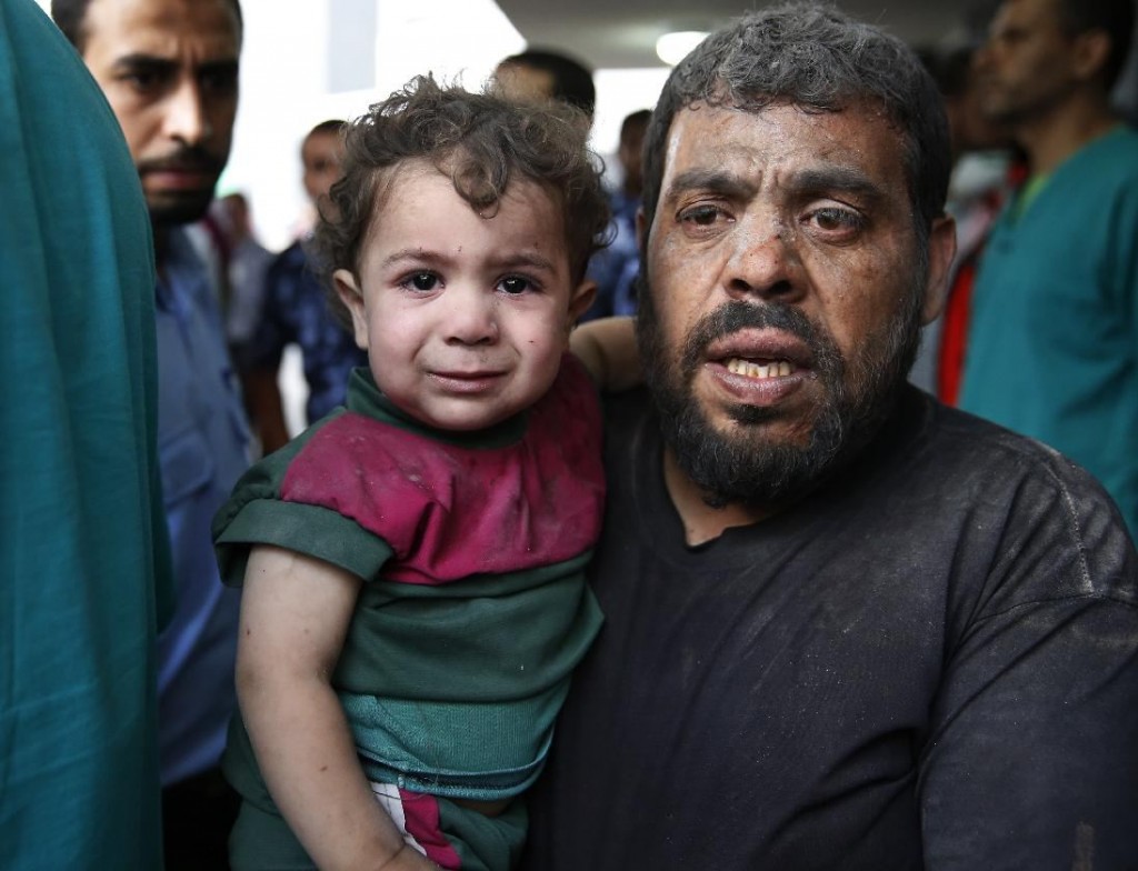 A Palestinian carries a wounded boy in the emergency room of Shifa hospital in Gaza City, northern Gaza Strip, Sunday, July 20, 2014. AP/Lefteris Pitarakis