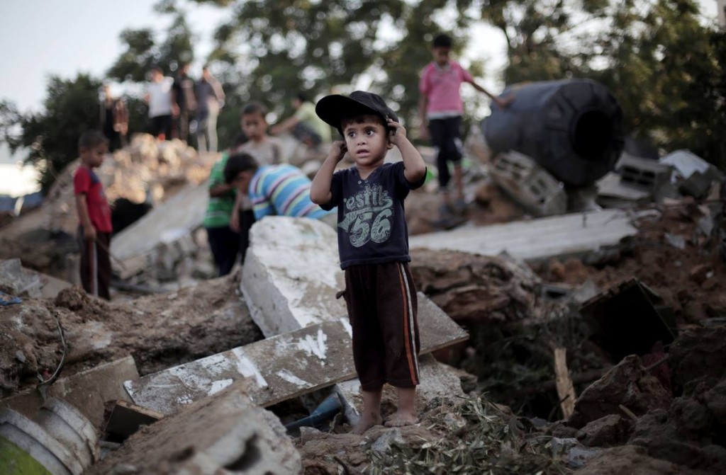 A Palestinian boy plays in the rubble of a destroyed house the day after an Israeli strike in the town of Beit Hanoun, northern Gaza Strip, Wednesday, July 9, 2014. (AP Photo/Khalil Hamra)