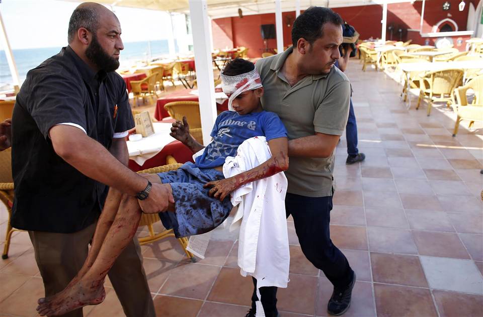 Employees and journalists carry a wounded boy into the hotel following an Israeli missile strike. Credit: Thomas Coex/AFP