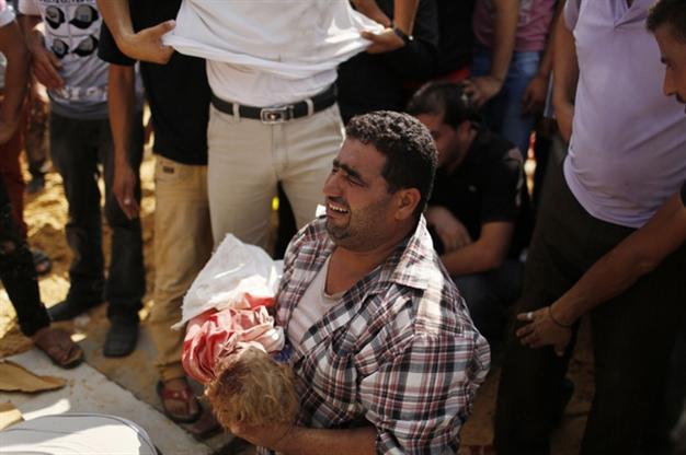 A relative cries as he carries the body of three-year-old Palestinian girl Haniyeh Abu Jarad, who medics said was killed along with her father and six other members from the same family by an Israeli tank shell, before her burial during their funeral in Beit Lahiya in the northern Gaza Strip July 19, 2014. REUTERS/Suhaib Salem