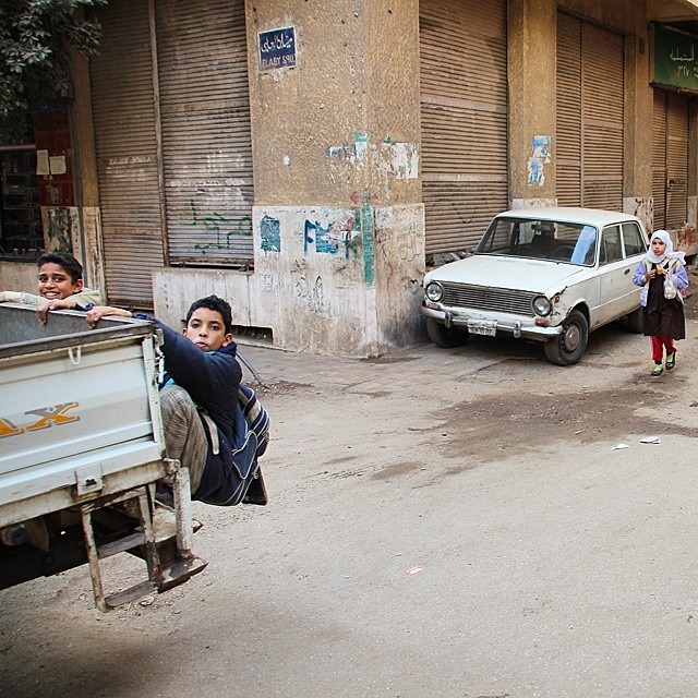 Boys catch a ride of the back of a pickup truck on their way home from school in the Haram district, Cairo. Photo by Shadi Rahimi