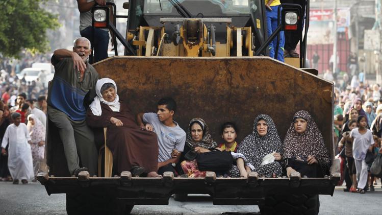 Palestinians sit in the bucket of an excavator as families flee the Shujayeh neighbourhood during heavy Israeli shelling in Gaza City July 20, 2014. REUTERS/Finbarr O'Reilly