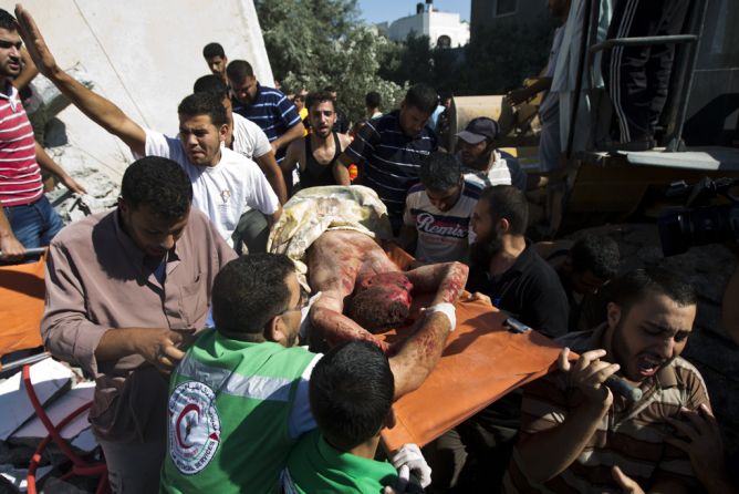 Emergency responders carry the body of a man, found under the rubble of his house following an Israeli airstrike on Maghazi refugee camp in central Gaza Strip on July 9, 2014. (MAHMUD HAMS/AFP/Getty Images)