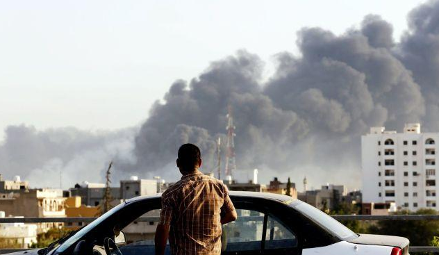 A man looks at smoke rising following an airstrike in Libya.