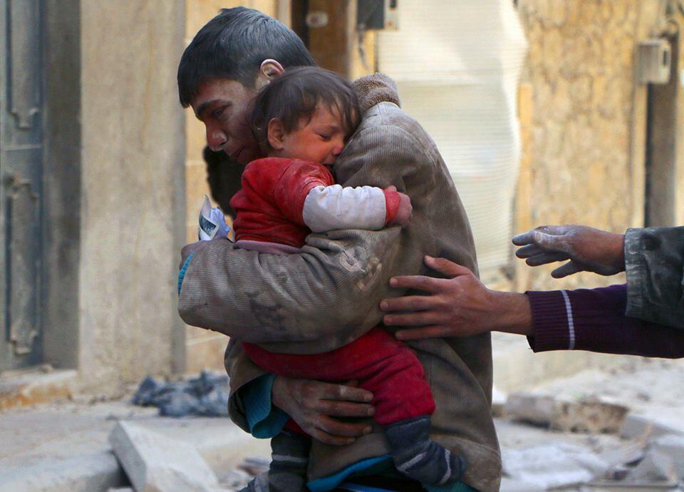 A boy rescues his sister from underneath the rubble of their home in Syria.