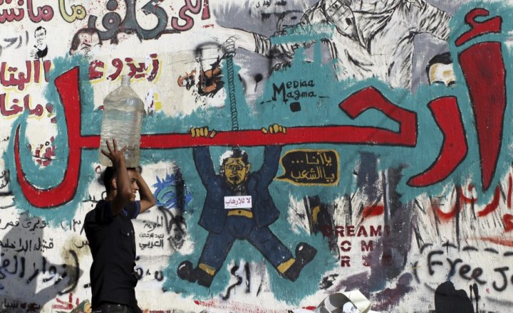 Graffiti artwork by the anti-MB campaign depicting Morsi dangling from the word “Leave.” In the artwork, Morsi is saying, “Either me…or the people.” (Photo credit: Reuters)