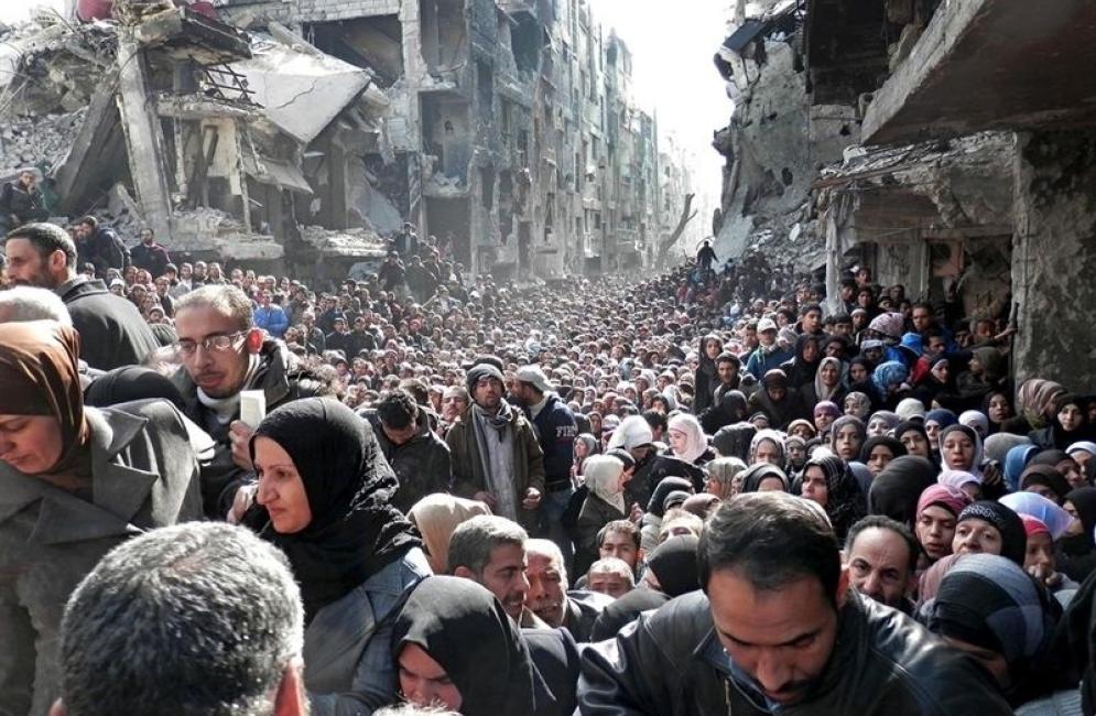 Refugees in Yarmouk wait to receive food from UNRWA in 2014.