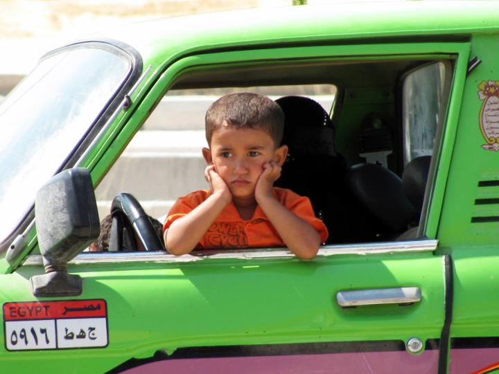 A child waiting for his father in a pickup truck to return from the market, North Coast