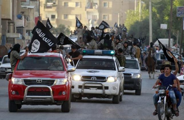 Militant Islamist fighters waving flags, travel in vehicles as they take part in a military parade along the streets of Syria's northern Raqqa province June 30, 2014.  REUTERS/Stringer