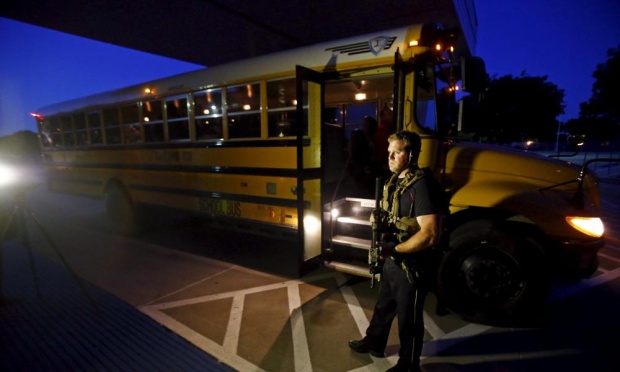 A police officer stands by a school bus used to evacuate attendees of the event under attack