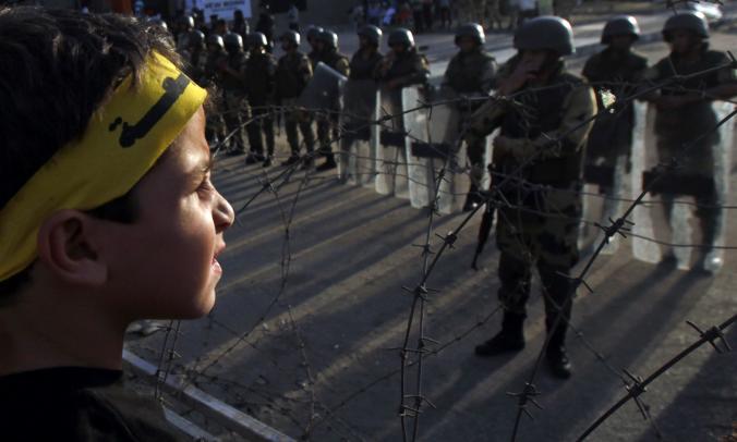 A boy, his headband inscribed with the word “Rabaa,” faces soldiers and riot police near Rabaa al Adawiya Square, which was home to the pro-Morsi sit-ins in 2013.  Credit: Amr Abdallah Dalsh/ Reuters