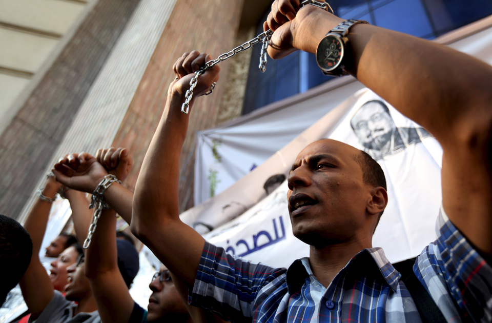 A protester holds up his hands, which are chained together, as journalists and activists protest against the restriction of press freedom and demand the release of detained journalists in front of the Press Syndicate in Cairo June 10, 2015 (Photo: Reuters)