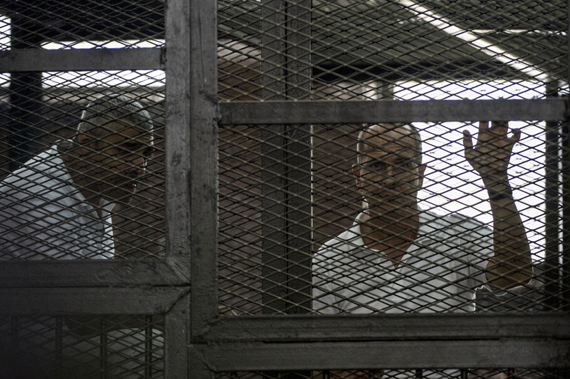 Mohamed Fahmy and Peter Greste listen to the verdict inside the defendants cage. Credit: Khaled Desouki/ AFP