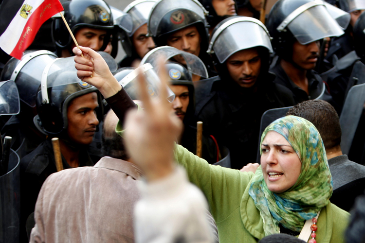 A woman holds an Egyptian flag in front of riot police during a protest in Cairo January 26, 2011.  Credit: Asmaa Waguih/ Reuters