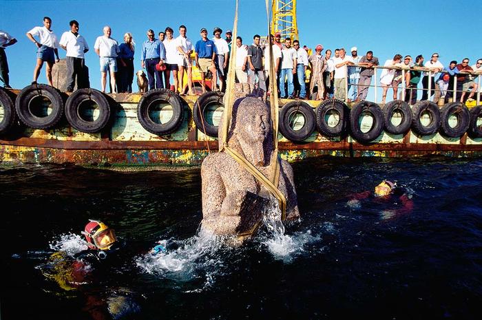 Franck Goddio and his team watch the rise to the surface of a colossal statue of red granite (5.4 m) representing the god Hapy, symbol of abundance and fertility and god of the Nile flood which stood in front of the temple of Heracleion. ©Franck Goddio/Hilti Foundation, photo: Christoph Gerigk
