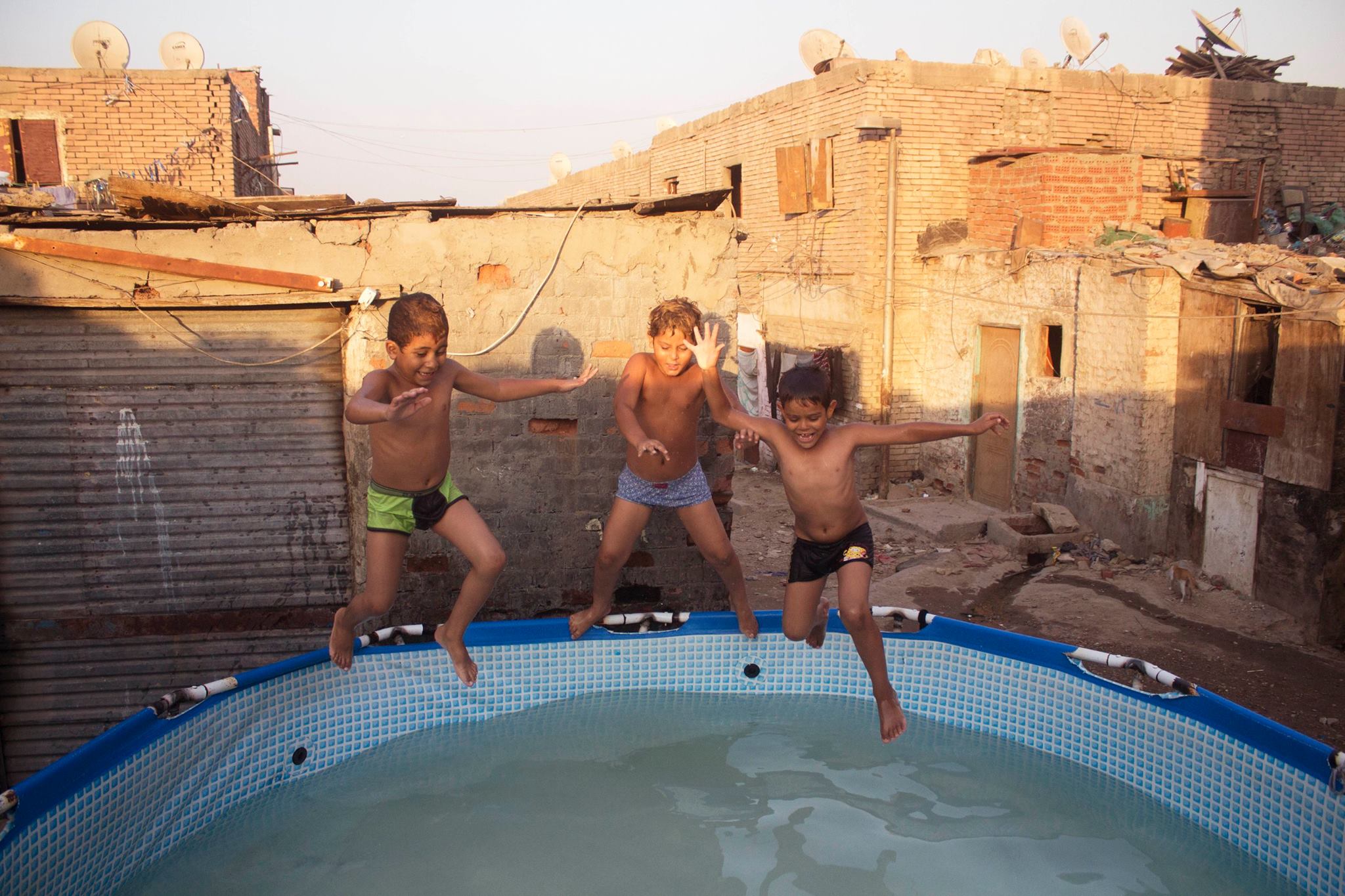 Children jumping in a 'public swimming pool' in Dwayka, Cairo.  Credit: Mostafa Darwish