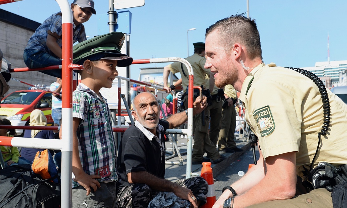 A German police officer talks to a young refugee as he waits for a bus outside the central railway station in Munich. Photograph: Christof Stache/AFP/Getty Images