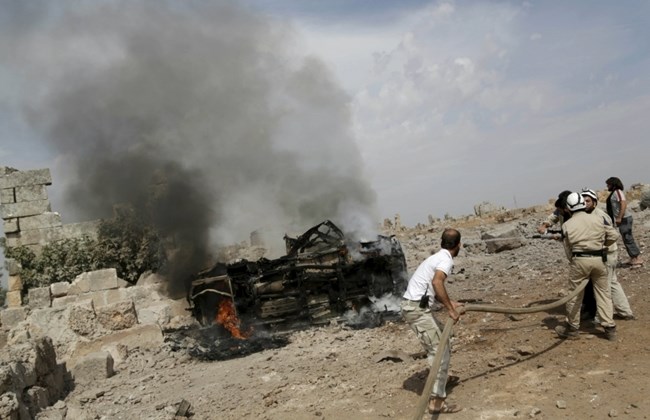 Civil defense members put out the flames on a burning military vehicle at a base controlled by rebel fighters from the Ahrar al-Sham Movement, that was targeted by what activists said were Russian airstrikes at Hass ancient cemeteries in the southern countryside of Idlib, Syria October 1, 2015. REUTERS/Khalil Ashawi