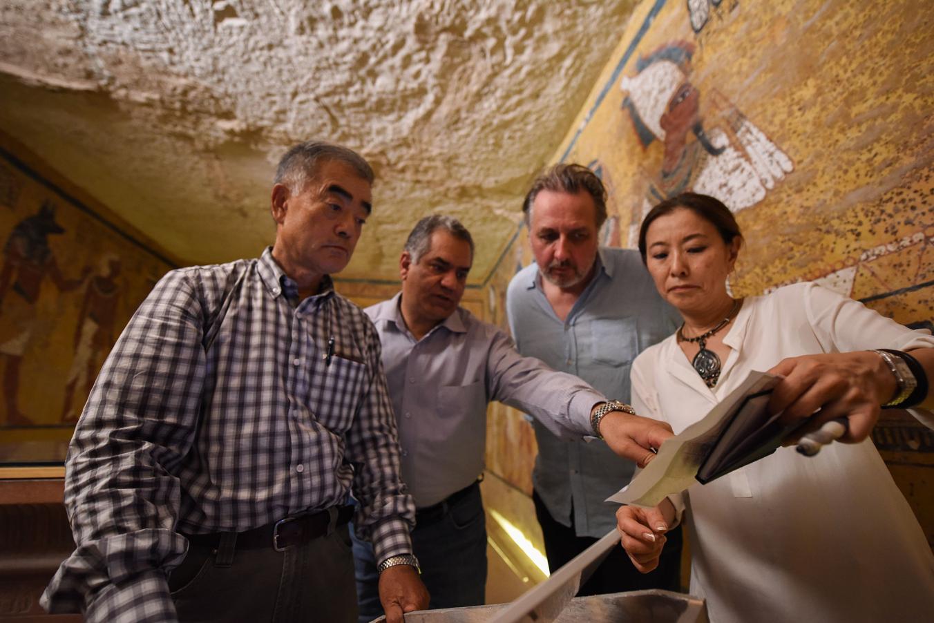 Hirokatsu Watanabe, Mamdouh Eldamaty, the Egyptian antiquities minister, and archaeologists Nicholas Reeves and Yumiko Ueno study an image of a painted wall scene. PHOTO: Brando Quilici, National Geographic