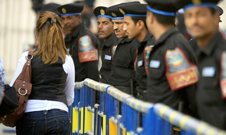 Policemen keeping guard of a facility near the Nile glare at a woman as she passes by. Credit: AP