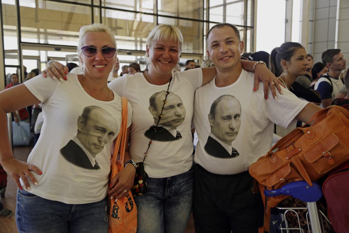 Russian tourists wearing t-shirts with images of Russian President Vladimir Putin pose for a photo in the departure terminal before boarding a flight from Sharm el-Sheikh (AP/Thomas Hartwell)