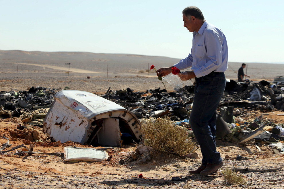 An Egyptian man lays flowers at the scene of the Russian passenger plane crash in Egypt's North Sinai.