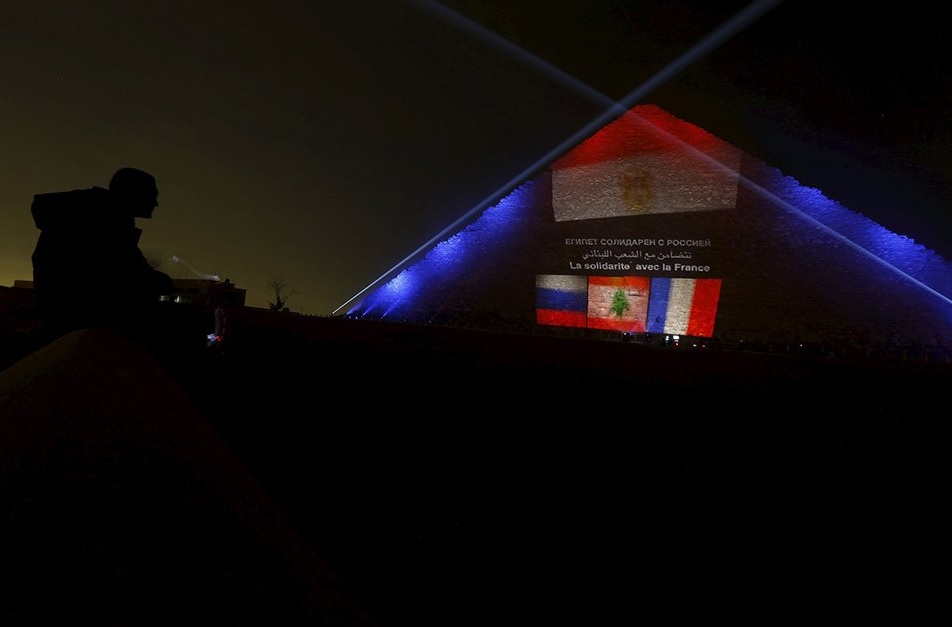 A man looks on as the Russian, Lebanese and French flags are projected on one of the Giza pyramids, in tribute to victims from the respective countries, on the outskirts of Cairo, Egypt, November 15, 2015. REUTERS/Amr Abdallah Dalsh