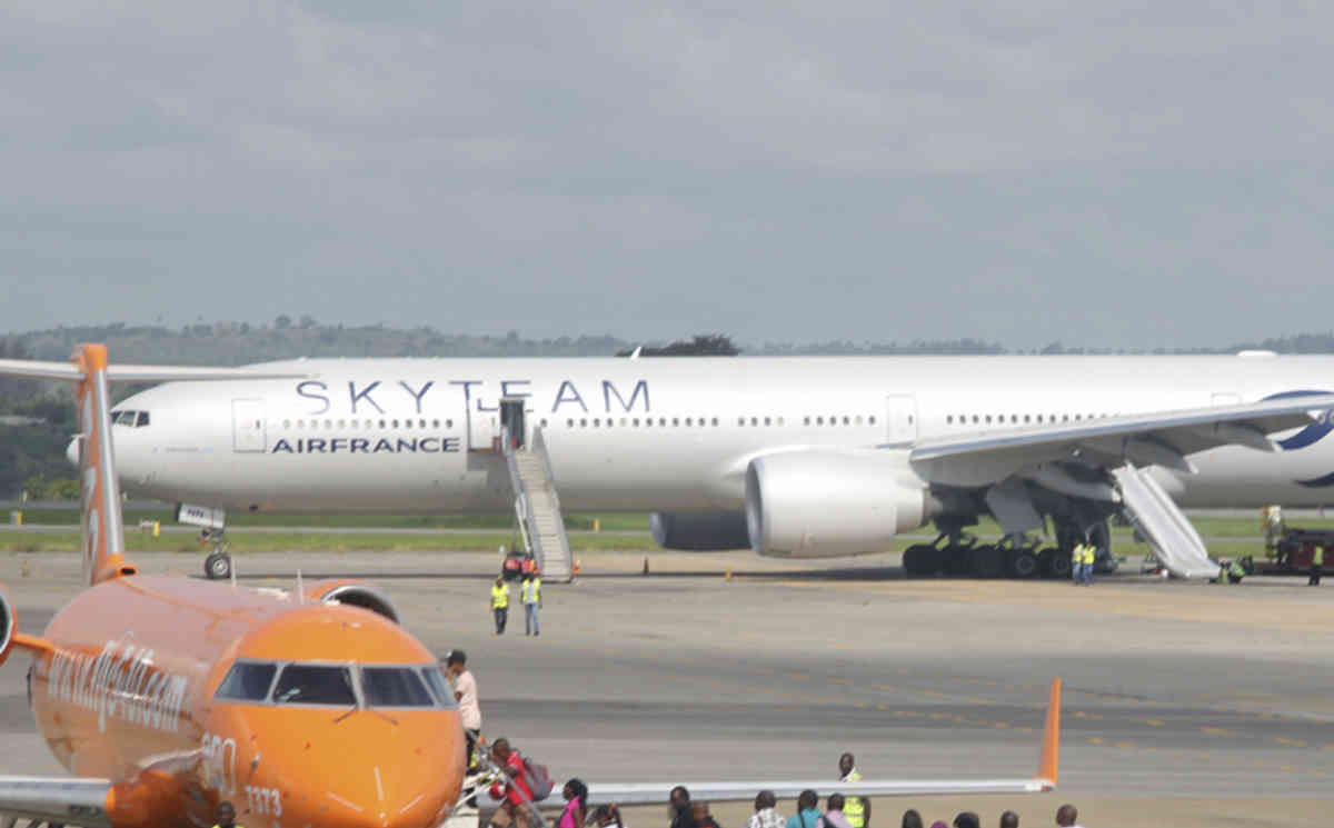 An Air France plane which made an emergency landing is seen behind passengers boarding on a small jetliner at Moi International Airport in Mombasa, Kenya Sunday, Dec. 20, 2015. The Boeing 777 Air France flight 463 from Mauritius to Paris was forced to land in the Kenyan coastal city of Mombasa after a device suspected to be a bomb was found in the lavatory, a Kenyan police official said Sunday. The passengers shown in this photo are not the Air France plane evacuees. (AP Photo/Edwin Kana)