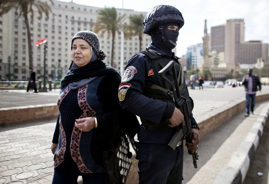 A woman walks past a security officer at Tahrir Square a day ahead of the January 25 Revolution's anniversary. Credit: AP
