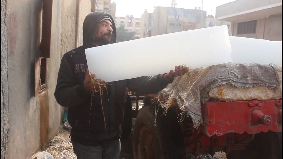 An ice factory worker carries ice blocks onto a truck. Photo: Aswat Masriya 