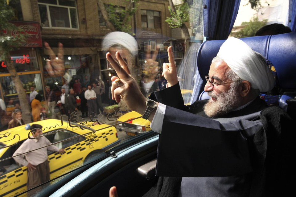 Iranian President Hasan Rouhani waves from his bus during his presidential election campaign tour in June 10, 2013, photo,. Credit: Vahid Salemi/ AP
