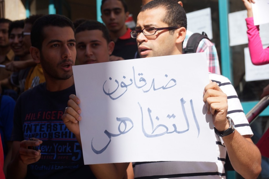 A protester holds a sign that reads, "Against the protest law." Photo: Tahrir News