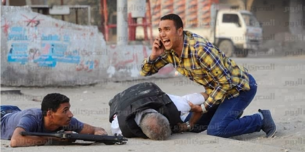 ournalist Tamer Magdy, without any vest or protection, cries for help and leaps to the side of Police General Nabil Farag