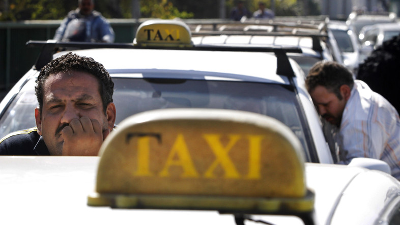 An Egyptian taxi driver peers over his car as he and others block part of 6th of October bridge in central Cairo, Egypt, Monday, March 25, 2013. (AP Photo/Amr Nabil)