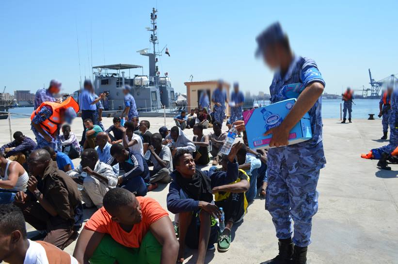Navy officers appear to be handing out water bottles to a group of refugees who were prevented from illegally migrating in September 2015. Credit: Military Spokesman