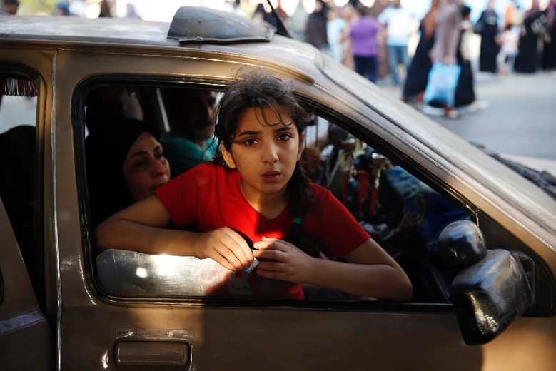 A Palestinian girl looks out from a vehicle while fleeing the Shujayeh neighbourhood during heavy Israeli shelling in Gaza City July 20, 2014. REUTERS/Finbarr O'Reilly