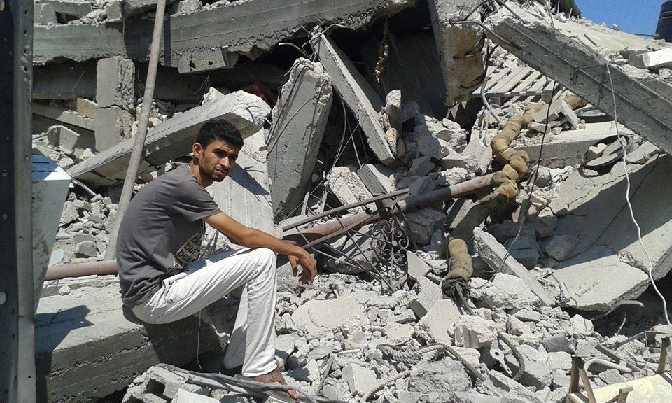 Abdalkareem sitting in the midst of rubble.