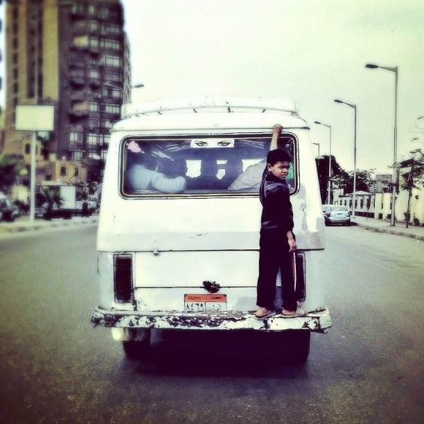 A child simply hanging off the back of a micro-bus in Giza. Photo by Roger Anis