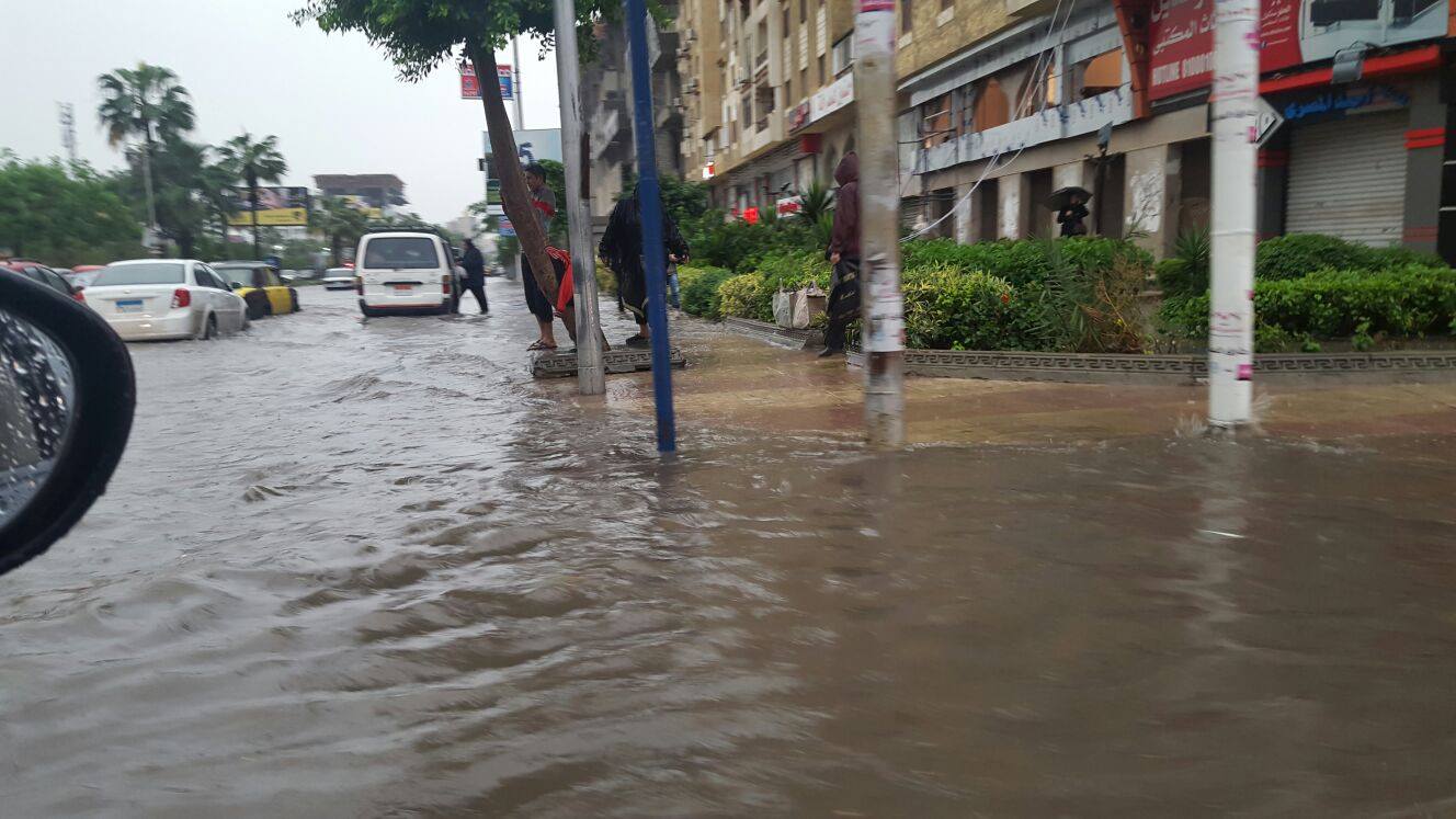 Alexandrian citizens try to find high ground as the rainwater floods the streets and pours over the sidewalks. Photo: Reem Sami Abul Enain