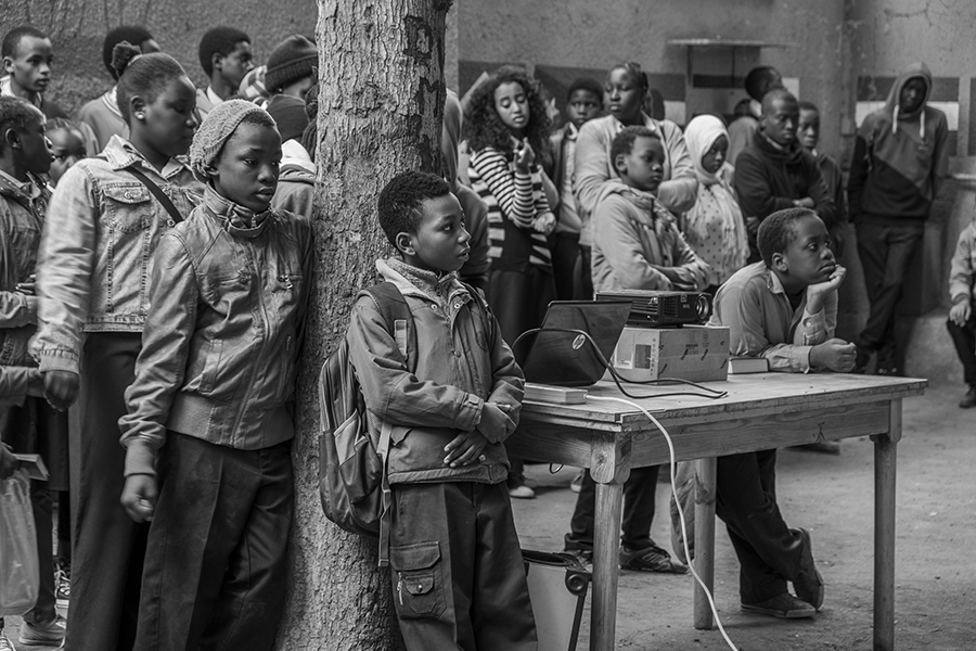 Students watch a movie being projected in the playground