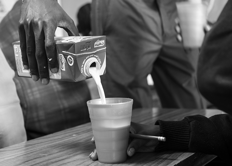 Teacher pouring milk for students during their lunch break